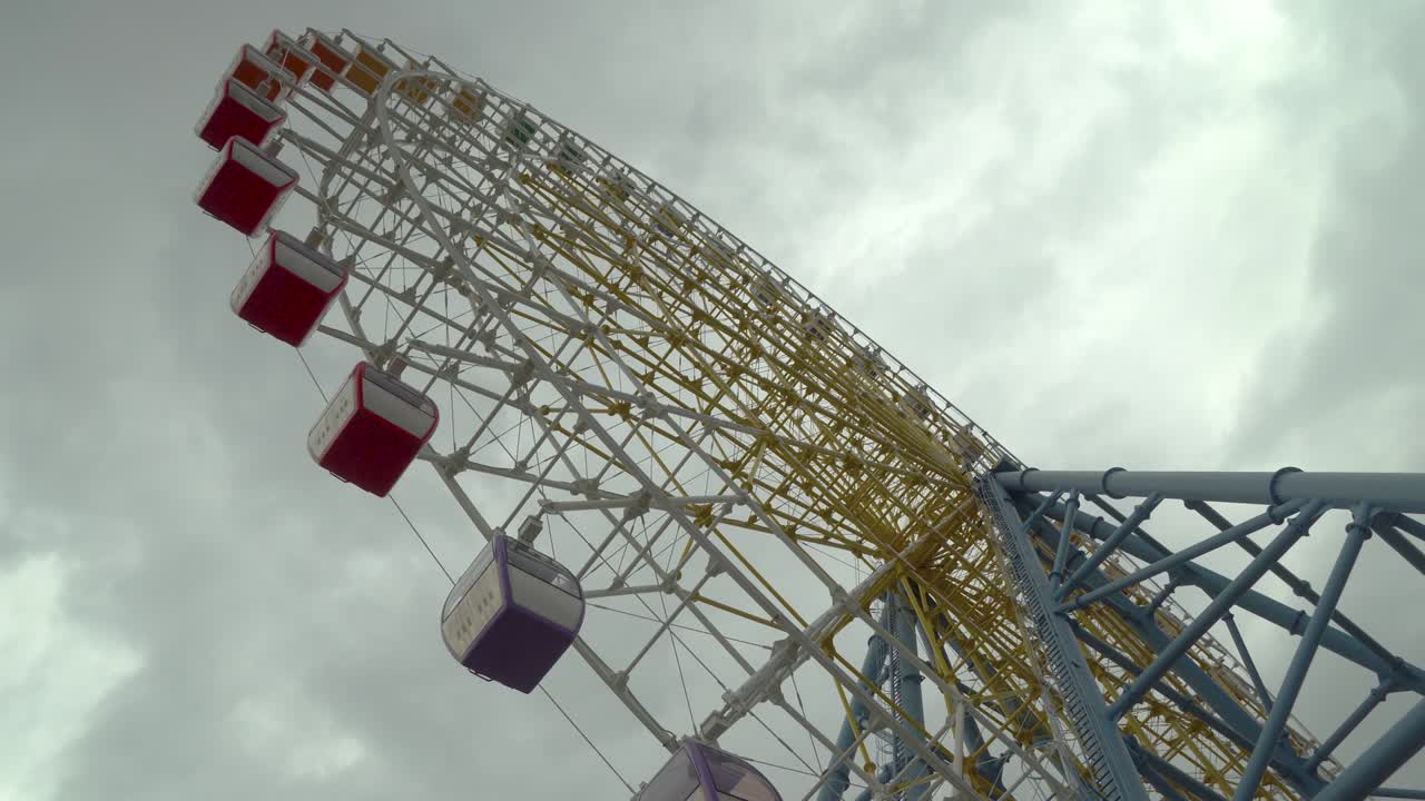 la rueda de la fortuna disparada contra las nubes y el cielo nublado. colores cálidos, luz del día.