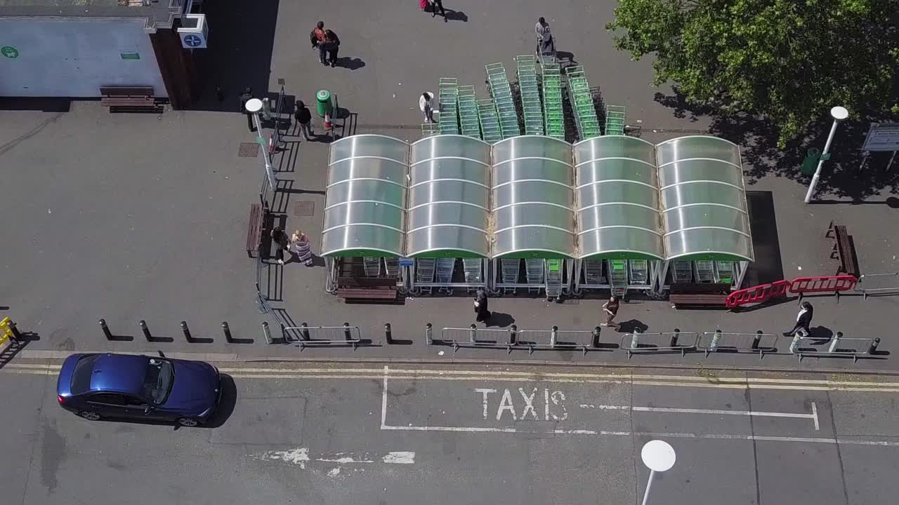 Aerial drone view of people getting into a queue for supermarket shopping while keeping their social distance as the security let them in in few groups to prevent overcrowding inside the store