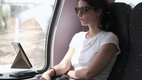 woman using smartphone and ebook on train, scenic journey