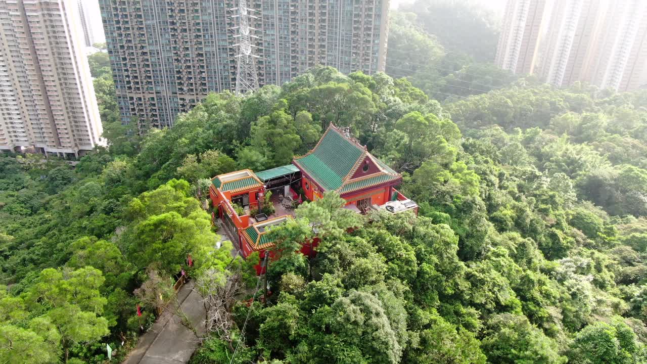 templo clásico en hong kong, rodeado de un exuberante terreno montañoso verde, vista aérea