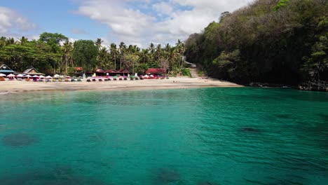 drone scene of virgin beach with tourists swimming in clear ocean in east bali, karangasem, indonesia