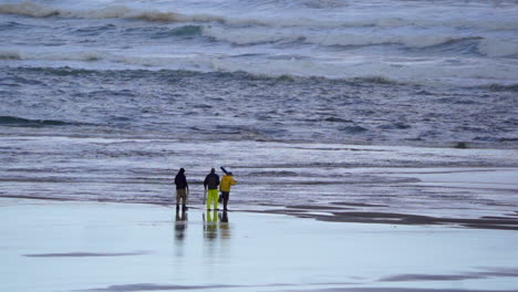 three men walking on the beach toward the surf