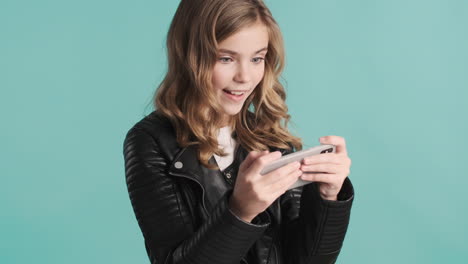 Teenage-Caucasian-girl-in-leather-jacket-playing-online-games-on-her-smartphone.
