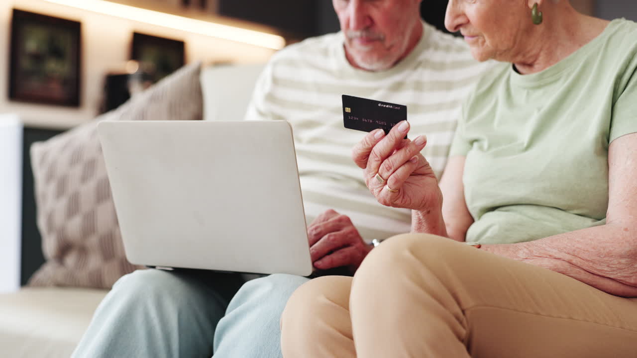 Coppia anziana che fa acquisti online con carta di credito sul portatile a casa