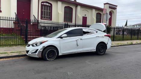 vandalized car parked on a poor neighborhood street in north america