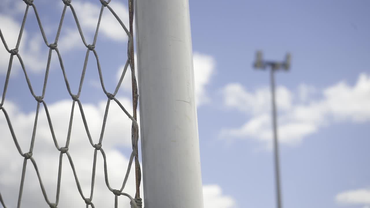 Metal soccer field net with illuminating poles rising against overcast sky, capturing empty stadium's athletic infrastructure and architectural detail