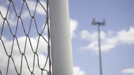 metal soccer field net with illuminating poles rising against overcast sky, capturing empty stadium's athletic infrastructure and architectural detail