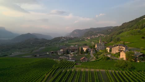 drone captures the village of pinzano in south tyrol during the golden hour, with the montagna village in the background