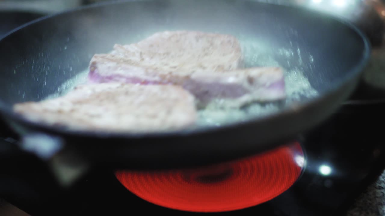 고단백 식사를 위해 팬에 참치 스테이크를 요리하는 동안 물 추가