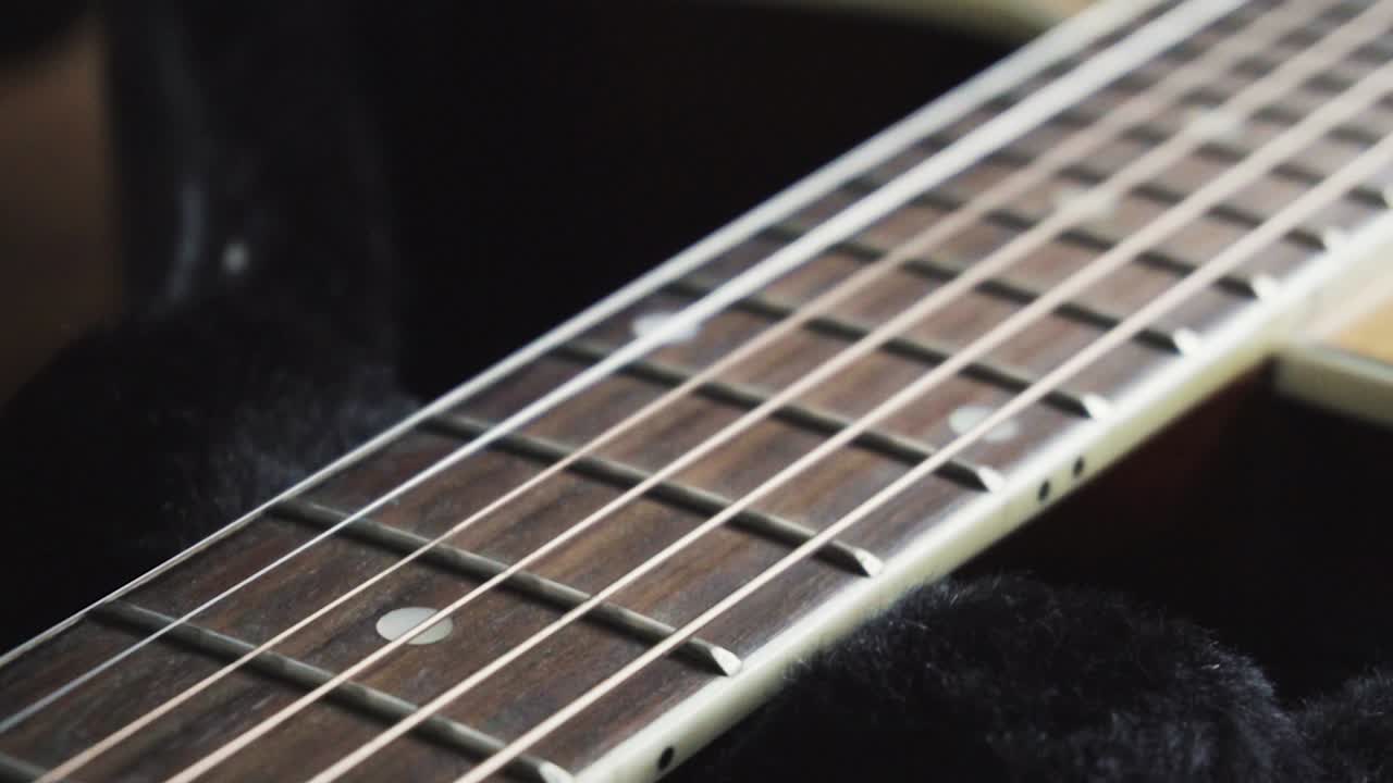 Slow motion close up panning shot of Acoustic Guitar strings.