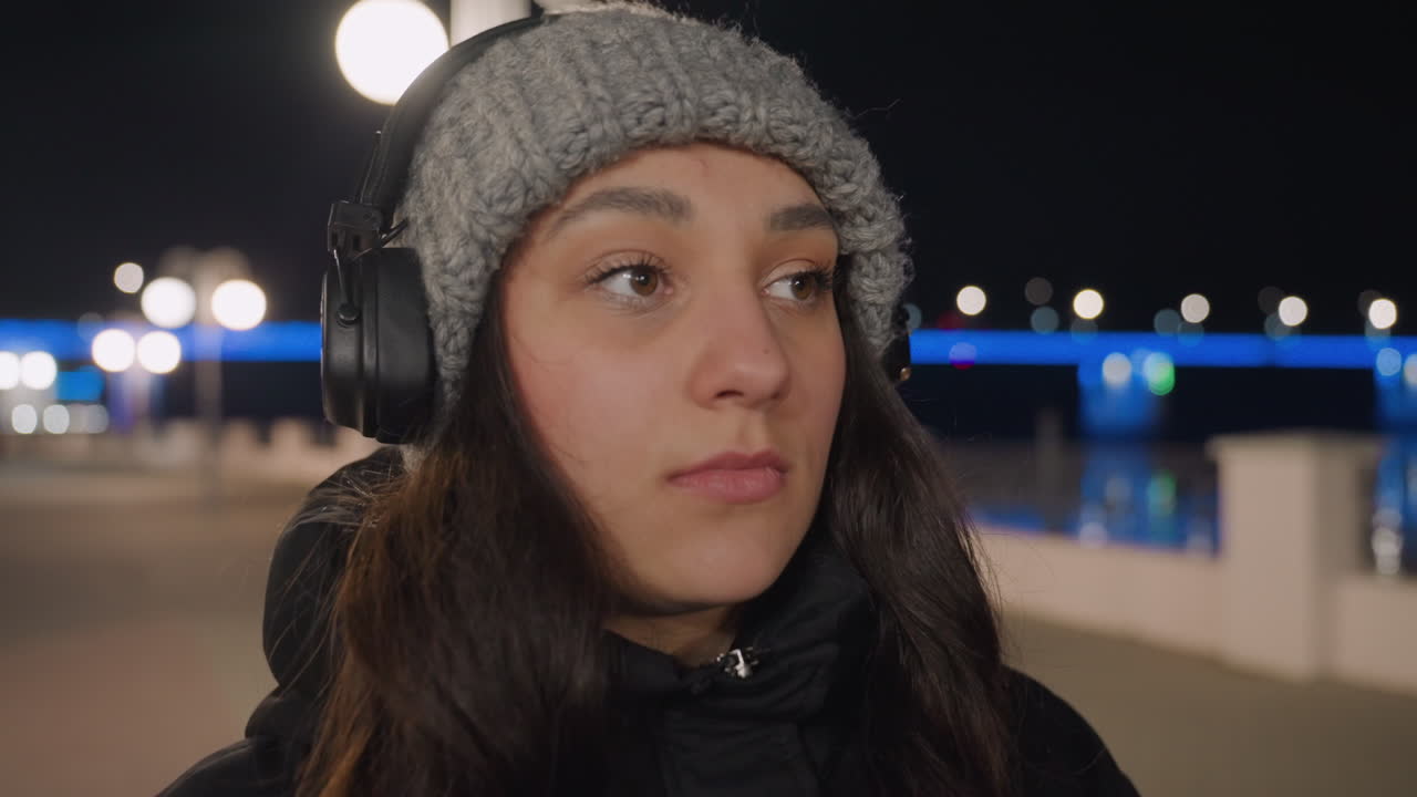 Midnight promenade white woman adjusting sunglasses before dance, confident headphone beat and bold gaze, city lights and bridge glow, winter coat movement with street performer energy