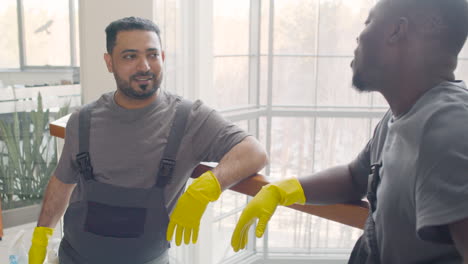 vista de cerca de hombres de limpieza árabes con guantes y uniforme hablando cerca de un carro de limpieza