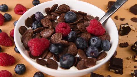 poner frambuesas en un tazón lleno de cereales para el desayuno