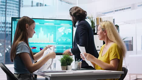 Mom-and-gen-Z-girl-checking-investment-plan-on-display-made-by-agent