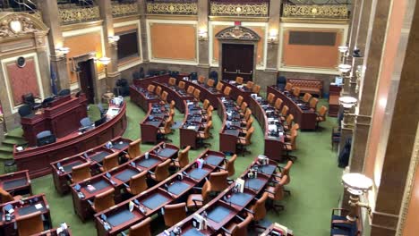 panning right to left looking across all the empty brown chairs and desks in the house chamber of the utah state capital