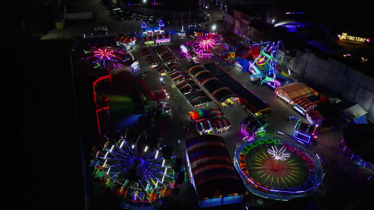 Nighttime aerial flyover of vibrant, colorful pop-up carnival at Virac Town Center, Catanduanes, Philippines.