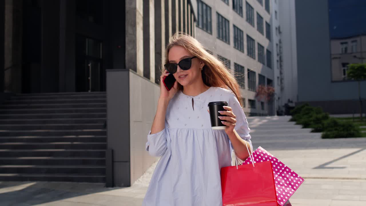 chica caminando desde el centro comercial con bolsas de compras y hablando en el teléfono móvil sobre la venta en black friday