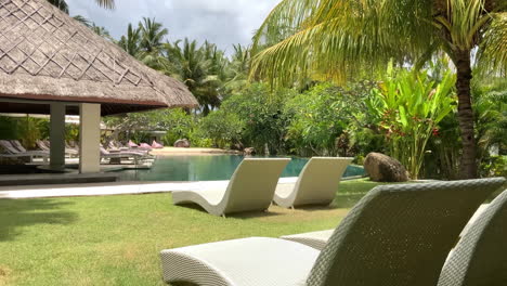 view of empty sun loungers on grounds beside swimming pool at tropical resort hotel in lombok, indonesia