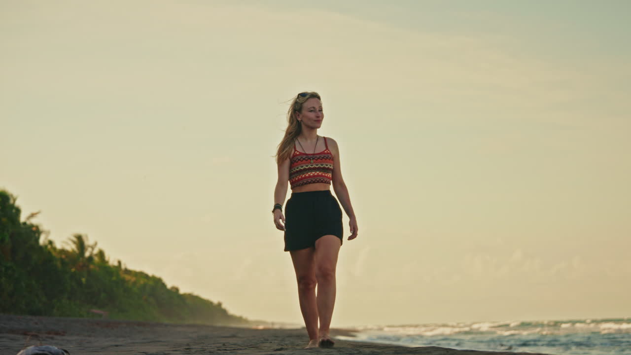 Young girl walking on the beach of Tortuguero National Park in Costa Rica enjoying the tropical vibes and waves coming to the shore.