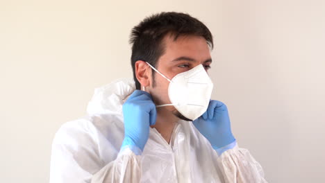 doctor in ppe suit putting on a face mask in profile to the camera and looking when finished