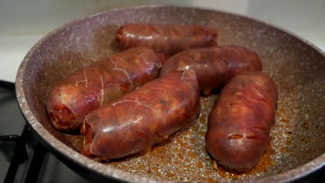 Primer-Plano-De-Algunas-Salchichas-De-Chorizo-Rojas-Grandes-Y-Brillantes-Que-Se-Cocinan-En-Una-Sartén