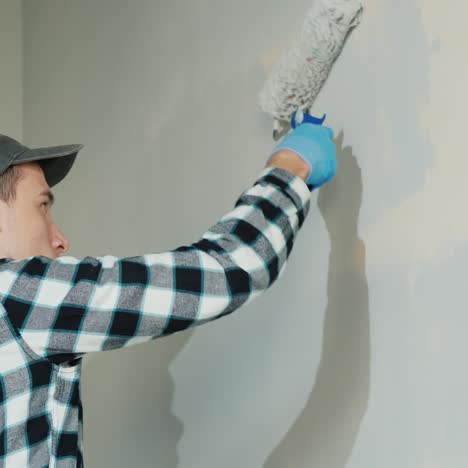 side view of male builder painting a wall with roller