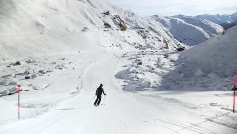 skier slowly making turns downhill on a clean white slope in the austrian alps