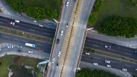 aerial drone shot looking straight down on a busy intersection highway bridge with lots of traffic and green surroundings in mexico