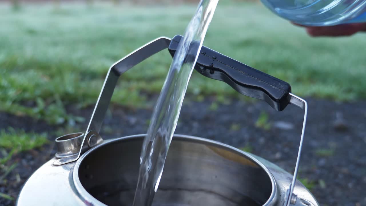 Riempimento di un bollitore da campeggio in acciaio inossidabile con acqua di sorgente - Primo piano
