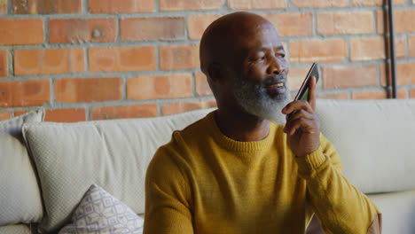 senior man talking on mobile phone in living room 4k