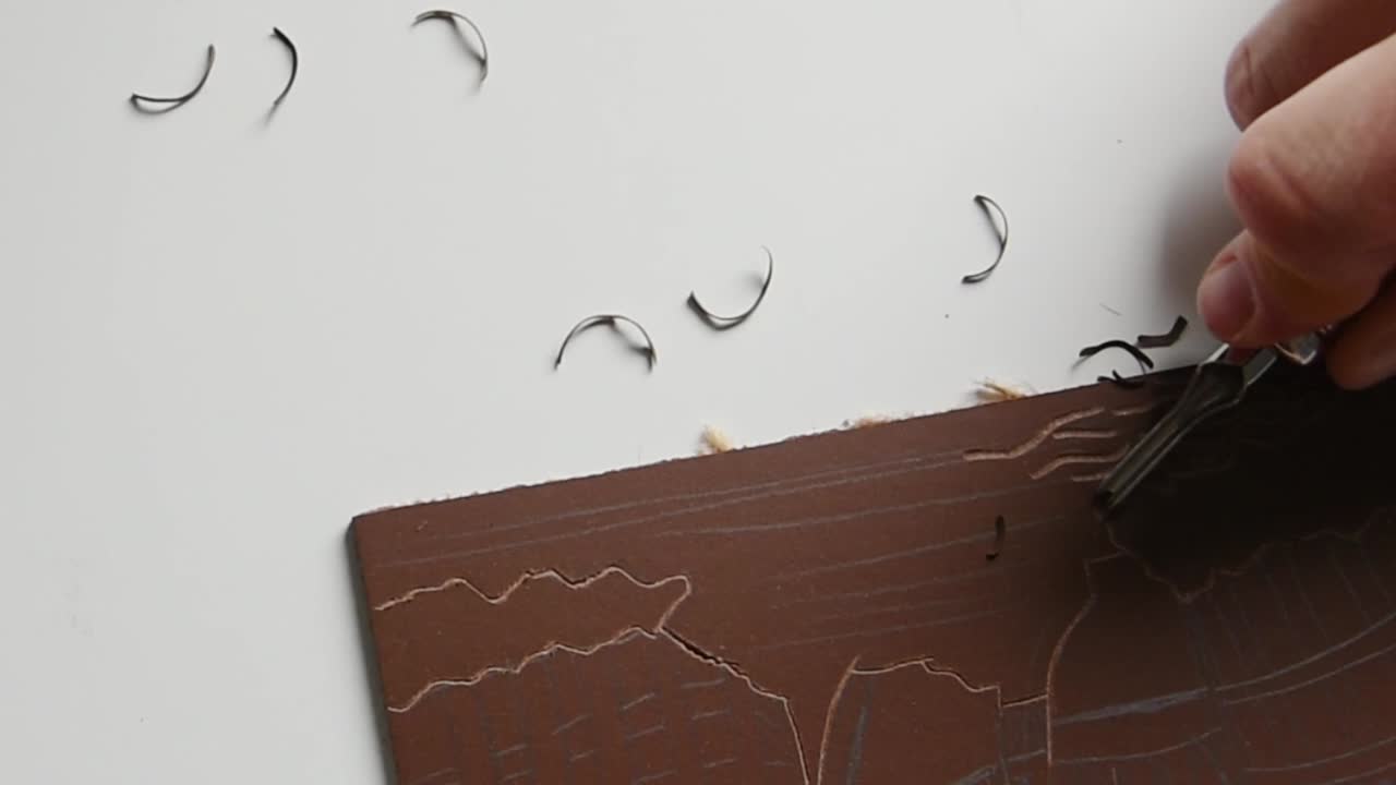 Slow motion view of linoleum carving with metal carving tool