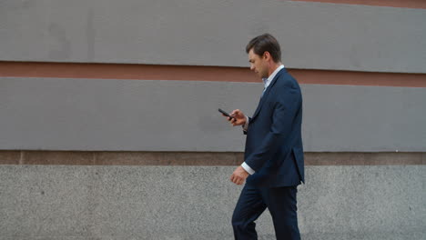 side view business man walking with phone. man using phone near modern building