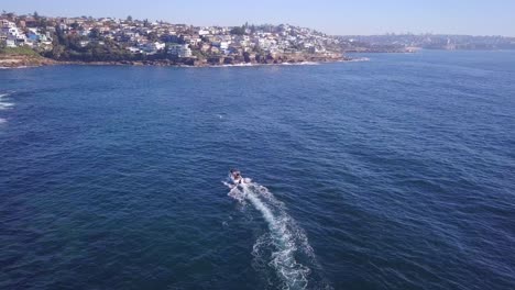 aerial fly over drone following a speed fishing boat at the sydney coastal beach seaside