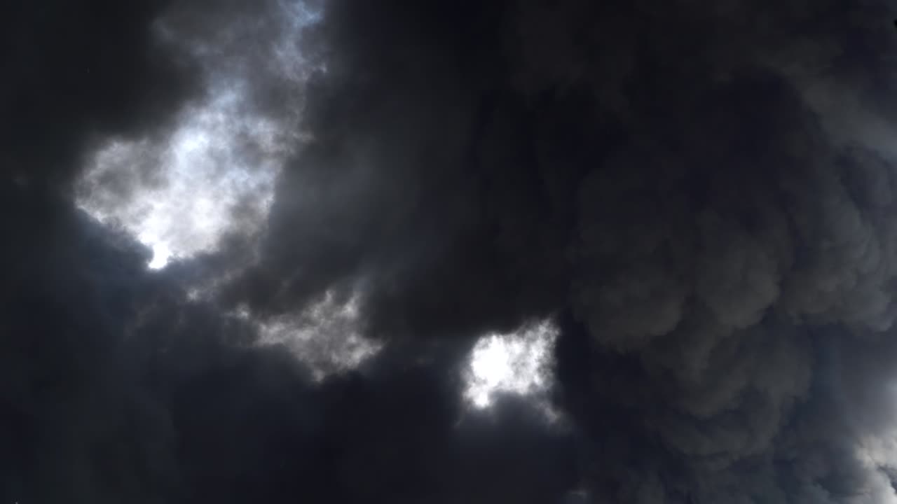 공장 건물에서 큰 화학 화재가 발생하고, 두꺼운 검은 연기가 하늘을 고 있다.