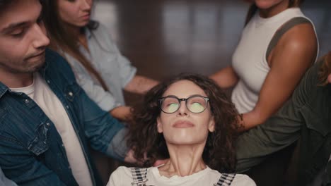 retrato en primer plano de una chica morena con cabello rizado en gafas que cae en manos de otros participantes en la terapia de grupo. practicar el apoyo mutuo en la terapia de grupo