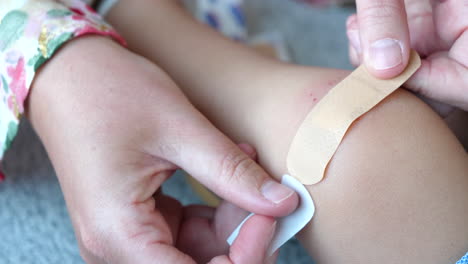 cerrar la mano de la madre poniendo una venda adhesiva en la herida de la rodilla del niño