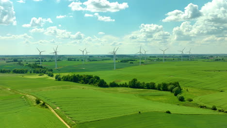 Luftaufnahme-Eines-Windparks-In-Einer-Ländlichen-Gegend-Mit-Windturbinen,-Die-über-Grüne-Felder-Unter-Einem-Strahlend-Blauen-Himmel-Mit-Flauschigen-Wolken-Verstreut-Sind