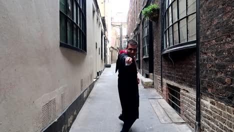 young man dressed as harry potter playing with wand casting magic spells in alley