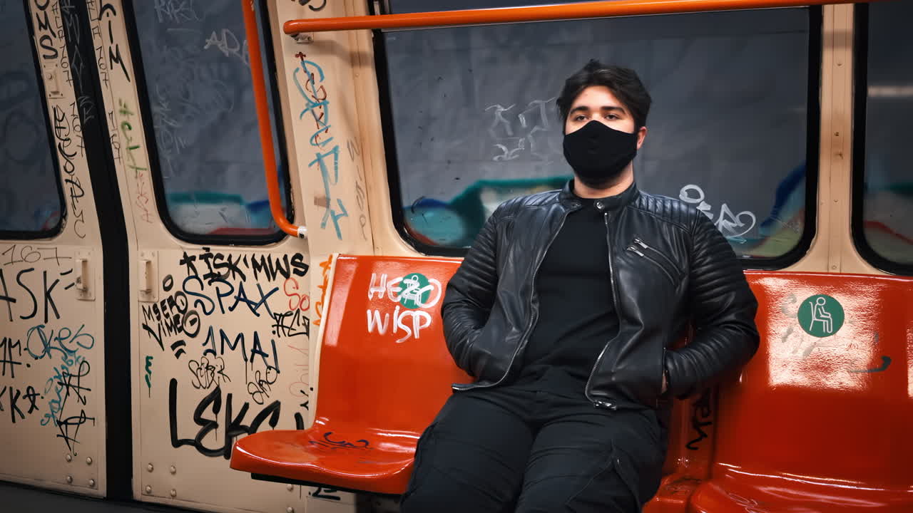 A caucasian man with beard in black medical mask in subway with painted interior, opening doors