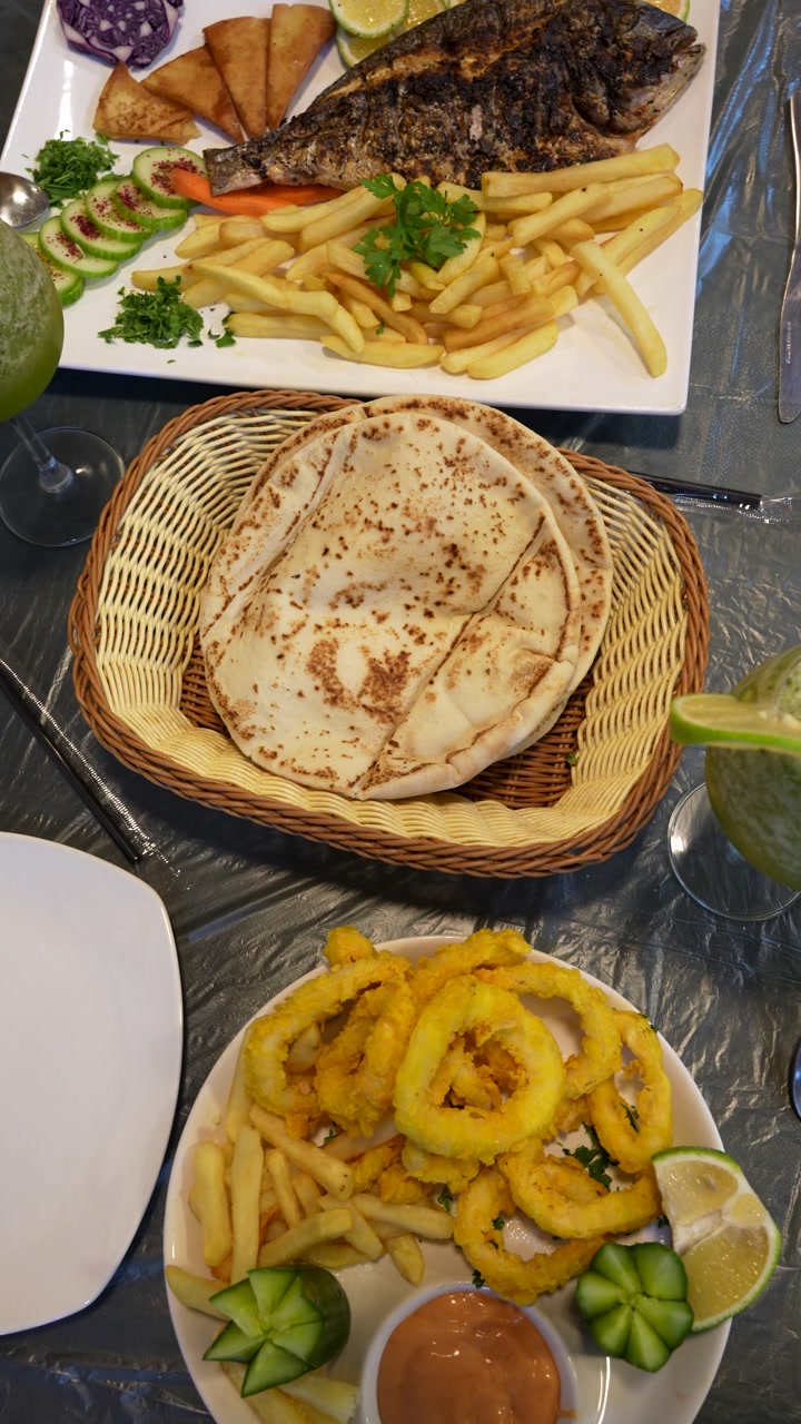 Mediterranean-style seafood meal grilled fish fried squid rings french fries and pita bread