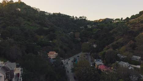 Volando-Sobre-El-Cañón-De-Laurel-Al-Atardecer,-Imágenes-De-Drones-Sobre-El-Icónico-Barrio-De-Los-Ángeles-Con-Caminos-Sinuosos-Y-Casas-Elegantes