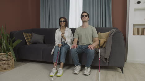 blind friends sitting on a sofa in a flat