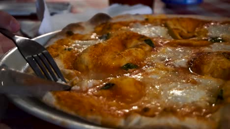 person slicing pizza with a knife and fork - spanish pizza