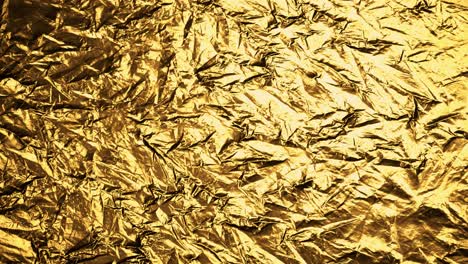 crumpled, golden foil shining in the soft spotlight. interesting, endless, seamless, abstract pattern of precious glossy metal looking luxurious and expensive. perfect background graphic.