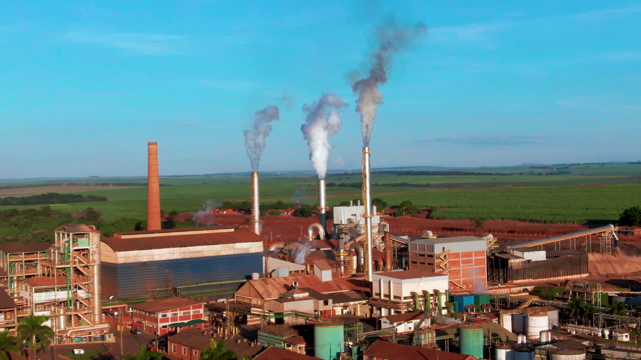 Drone aerial landscape of steam fumes coming from steel turbines at ethanol production plant factory buildings and facility in rural countryside Brazil South America industry processing warehouse