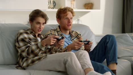 happy couple holding joysticks losing in video game. upset players rest on sofa.