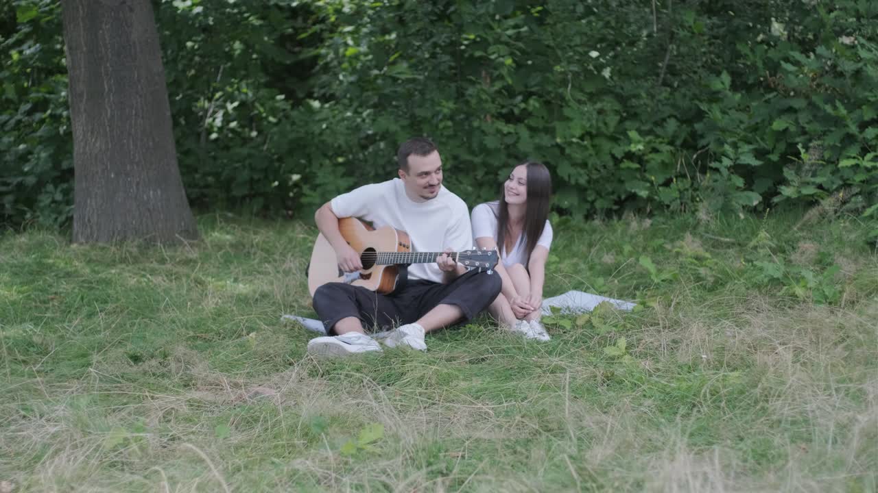 Couple sitting in the park playing guitar