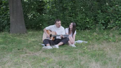 couple sitting in the park playing guitar