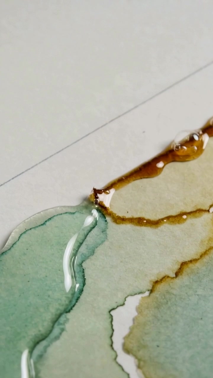 Video verticale: Che mostra una traccia di lavaggio acquamarina-marrone su carta acquerello, con una goccia trasparente che guida il flusso capillare.