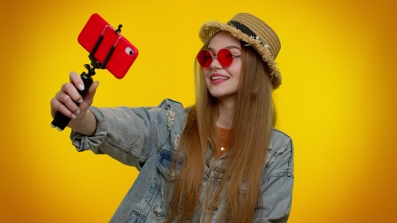 blogger viajera con gafas de sol, tomando selfies en el teléfono móvil, comunicándose por video llamada en línea